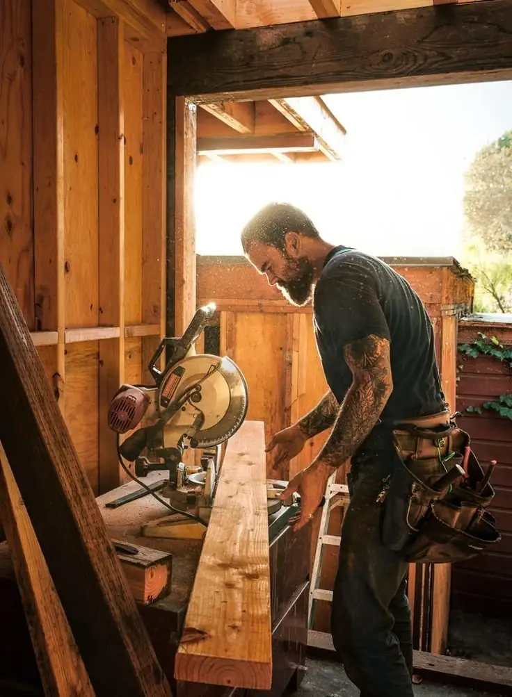 A carpenter cutting timber on a mitre saw on a building site